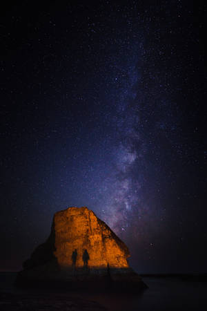 兩人在星空下站在發光的岩石上，銀河可見。