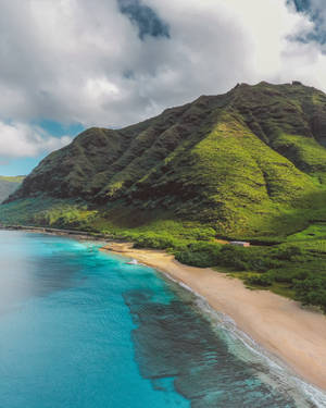 碧綠海洋與沙灘相接，旁邊是青山，天空多雲。 — 沙灘 壁紙