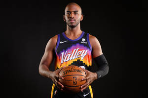 專業籃球運動員身穿太陽隊球衣，在黑色背景前手持 Spalding 籃球。
