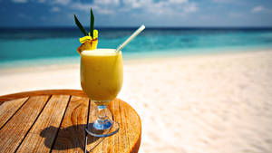 沙灘桌上的熱帶飲品，可欣賞海景 — 16:9 壁紙