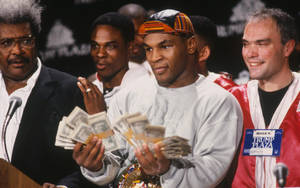 Mike Tyson 喺拳擊記者活動中手持現金同冠軍腰帶。