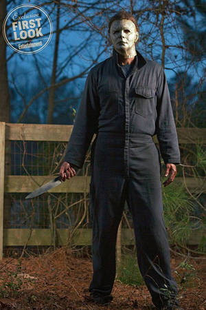 Michael Myers 在黃昏時分的樹林地區手持刀。