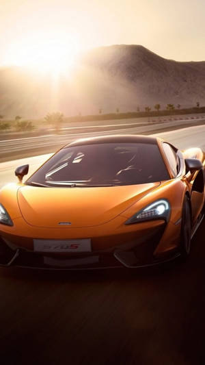 橙色McLaren 570S在日出時於沙漠高速公路上奔馳。