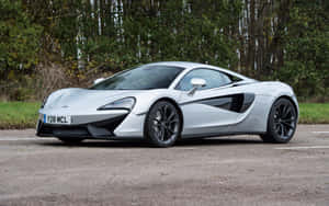 銀色McLaren跑車停在瀝青上，靠近樹木。