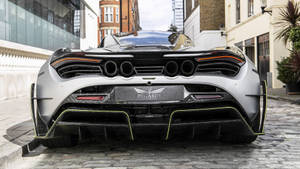 銀色McLaren Pegasus超跑帶黃色飾邊停泊在鵝卵石街道。 — 4K 法拉利 壁紙
