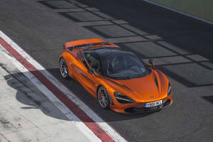 橙色McLaren 720S在日落時分的賽道上飛馳。 — 4K 法拉利 壁紙