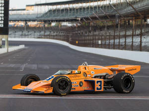 黃昏時分空賽道上的橙色復古McLaren賽車。 — 4K 法拉利 壁紙