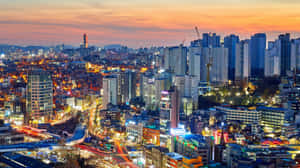 黃昏時分繁華的城市，發光的建築物和繁忙的道路。 — 日落大道 壁紙