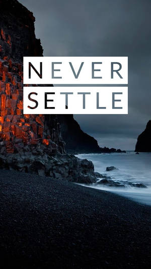 文字疊加在黃昏時分的黑暗岩石海灘上顯示「never settle」。 — OnePlus 壁紙