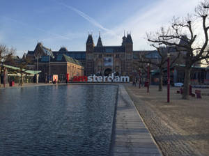 阿姆斯特丹博物館，帶有「I amsterdam」標誌和反射池，日落時分。 — 建築 壁紙