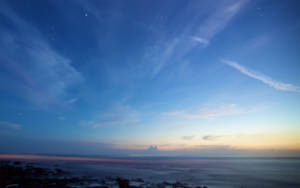 暮色海景，星空與雲朵在岩石海岸上方