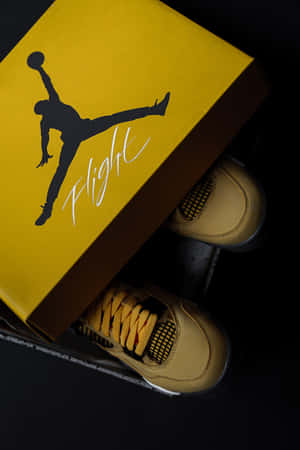 淺褐色 Jordan 運動鞋旁放著帶有 Jumpman 標誌的黃色品牌鞋盒。