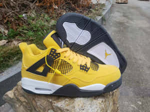 黃色 Jordan 4 運動鞋在戶外石頭上展示。