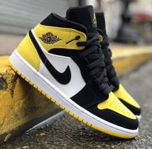 黑黃色 Air Jordan 1 運動鞋靠在一條黃色路邊石上。