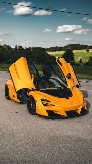 橙色McLaren跑車在鄉村道路上打開鷗翼車門。