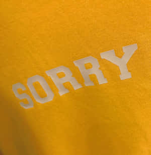 金黃色T恤，白色粗體「SORRY」文字。