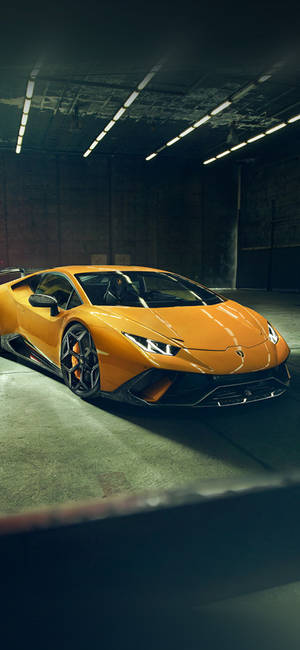 昏暗工業車庫中的橙色林寶堅尼Huracán。 — iPhone 17 Pro 壁紙