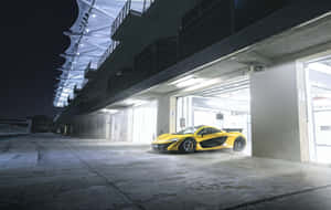 夜間停放在賽車場車庫的黃色McLaren跑車。