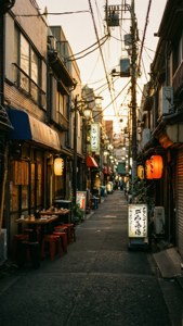 日落時分，狹窄的日本街道上掛著發光的燈籠和傳統商店