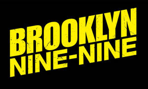 黑色背景上帶磨損紋理的粗體黃色「Brooklyn Nine-Nine」標誌。