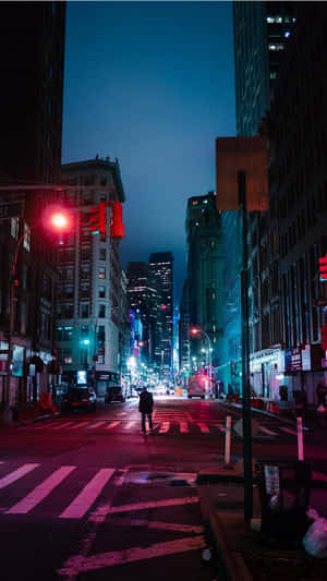一個人在夜晚穿過濕漉漉的城市街道，下方是發光的紅色交通燈和高樓大廈。