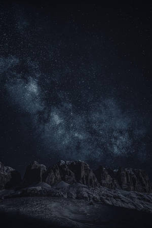 積雪的山脈在繁星點點的夜空下，銀河清晰可見。 — 黑色 iPhone 壁紙