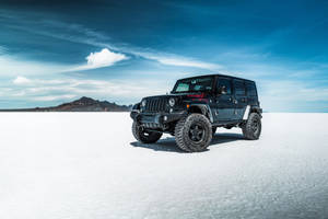 黑色Jeep Wrangler停在白色鹽灘上，遠處有山。