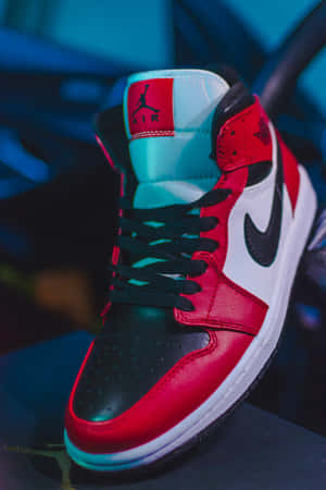 紅、黑、白色Jordan 1運動鞋，帶有青綠色點綴，在藍色燈光下。