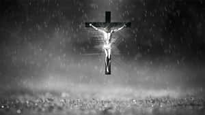 在雨中發光的 crucifixion 人物，映襯著黑暗的暴風雨天空。 — 交叉 壁紙