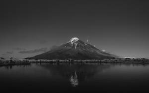 雪山峰在陰天倒映在靜止的水面上。