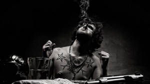 一個有紋身的男人在黑暗環境中吸煙，附近有一把槍。 — 紋身 壁紙