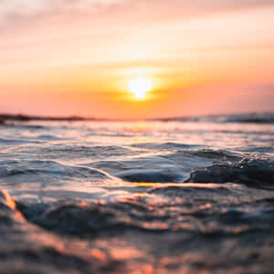 夕陽映照海浪，呈現溫暖的橙色和粉紅色調 — iPad Pro 13 壁紙