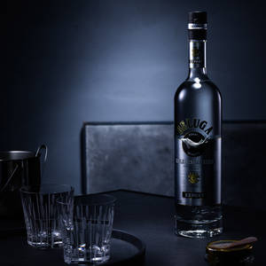 Beluga伏特加酒瓶與酒杯在深色吧檯上。