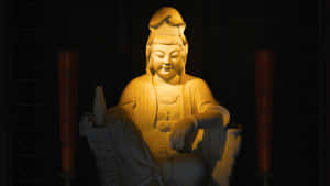 一尊柔和照明的佛像，旁邊有蠟燭，在昏暗的房間裡。