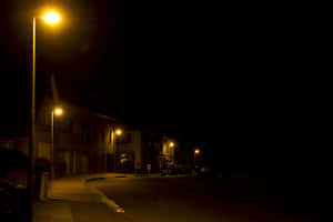 黃色街燈照亮的夜晚街道，有黑暗的建築物和潮濕的路面。 — 夜晚 GIF 壁紙
