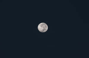 滿月位於沒有雲或星星的黑暗夜空中央。