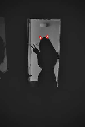 在門口中，帶有紅色惡魔角做出和平手勢的人的剪影。