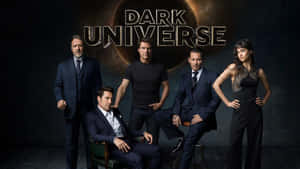 五位演員身穿深色正裝，在帶有'Dark Universe'文字的宇宙日食背景前擺姿勢。