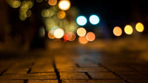 夜晚的鵝卵石街道，帶有來往車輛和街燈的模糊彩色燈光。