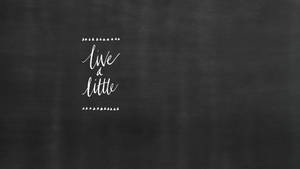 黑板上有白色手寫語錄「live a little」。