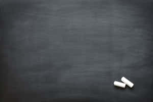 深灰色黑板表面上的兩支白色粉筆。