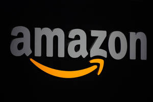 黑色背景上帶有灰色字母和橙色箭頭的Amazon標誌。