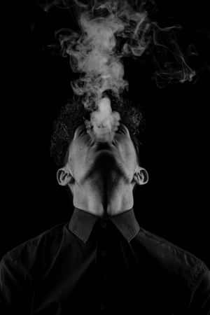 男人在黑白工作室肖像中向上呼出煙霧。