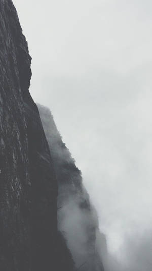 多雲天空下，山地景觀中的迷霧懸崖峭壁。
