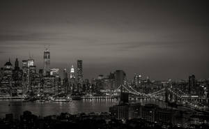 紐約天際線的黑白夜景，有明亮的建築物和水上的橋樑。