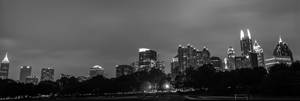 夜晚的城市天際線，有燈光建築和前景的黑暗樹木 — 黑白 壁紙