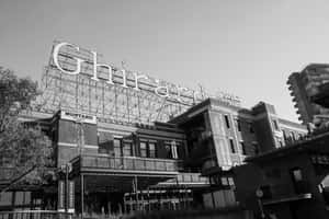 Ghirardelli 標誌位於一座帶有陽台和腳手架的歷史磚砌建築上。 — 黑白 壁紙