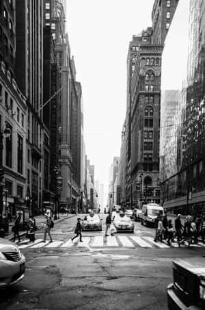 行人穿過一條兩旁高聳歷史建築的繁忙城市街道。 — 小米18 Fold 壁紙