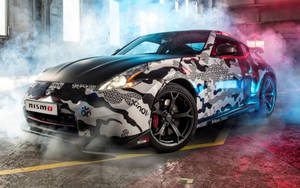 黑白迷彩日產370Z Nismo在煙霧瀰漫的車庫中漂移，帶有彩色燈光。