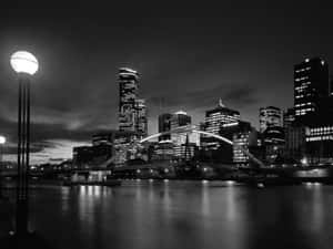 夜間城市天際線，發光的橋樑和摩天大樓倒映在水中。 — 城市景觀 壁紙